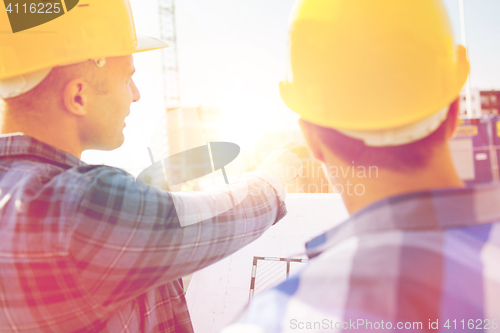 Image of close up of builders with blueprint at building