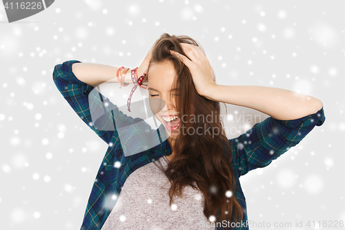 Image of happy teenage girl holding to head over snow