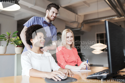 Image of happy creative team with computer in office