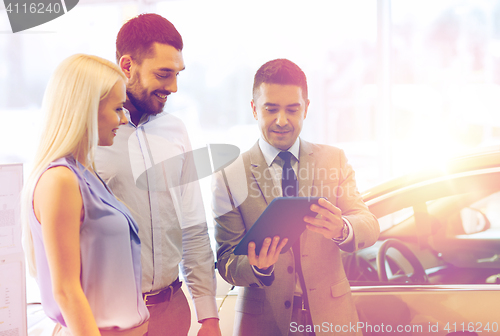 Image of happy couple with car dealer in auto show or salon