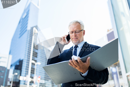 Image of senior businessman calling on smartphone in city