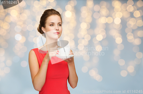 Image of woman in red with cup of coffee over lights