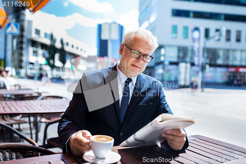 Image of senior businessman with newspaper drinking coffee