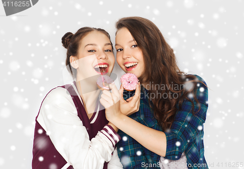 Image of happy pretty teenage girls eating donuts