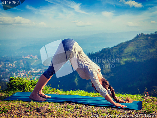 Image of Young sporty fit woman doing yoga oudoors in mountains