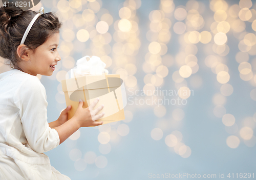 Image of smiling little girl with gift box over lights