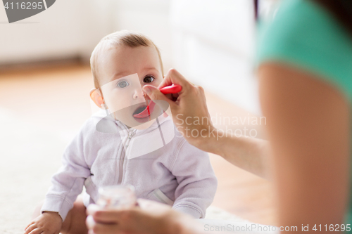 Image of mother with spoon feeding little baby at home