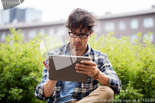 Image of man in glasses with tablet pc on city steet