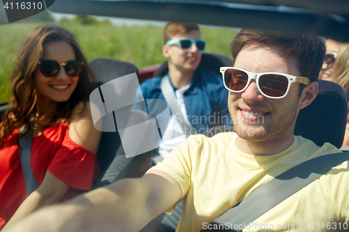 Image of happy friends driving in cabriolet car