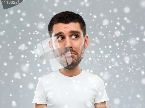 Image of unhappy young man over snow background