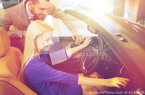 Image of happy couple buying car in auto show or salon