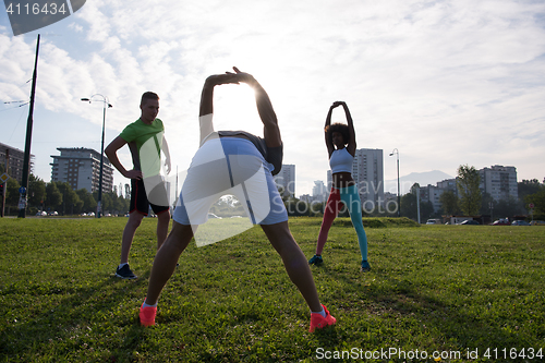 Image of multiethnic group of people stretching in city park