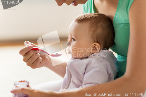 Image of mother with spoon feeding little baby at home