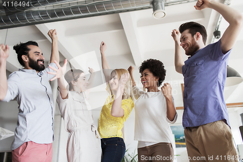 Image of happy creative team celebrating victory in office