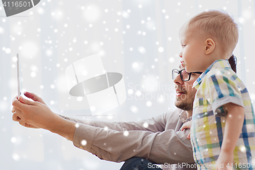 Image of father and son with tablet pc playing at home