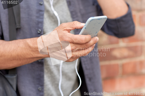 Image of close up of man with smartphone and earphones wire