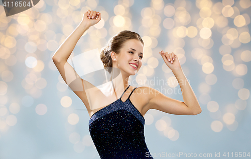 Image of happy woman dancing with raised hands over lights