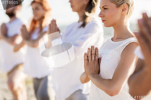 Image of people making yoga on summer beach