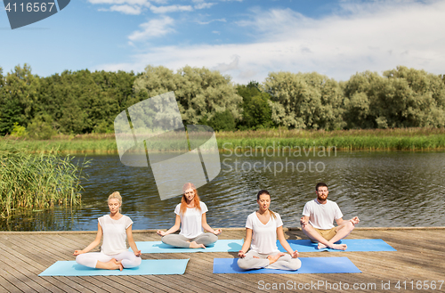 Image of people meditating in yoga lotus pose outdoors