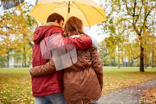 Image of happy couple with umbrella walking in autumn park