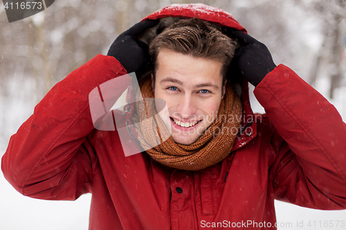 Image of happy man in winter jacket with hood outdoors