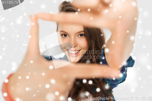 Image of teenage girl making frame of fingers over snow