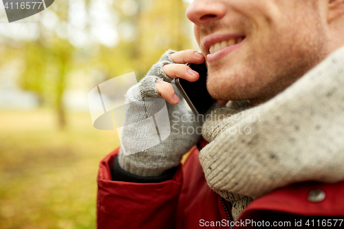 Image of close up of man with smartphone calling in autumn