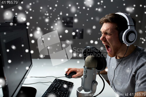 Image of man in headset playing computer video game at home