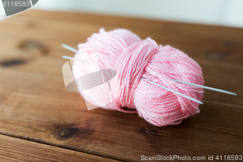 Image of knitting needles and ball of pink yarn on wood