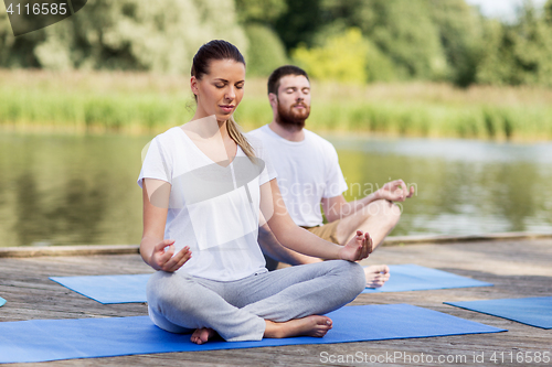 Image of people meditating in yoga lotus pose outdoors