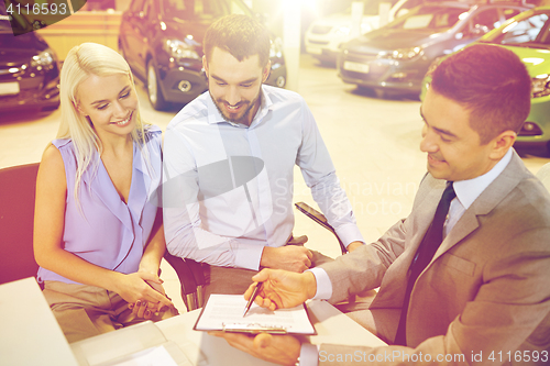 Image of happy couple with car dealer in auto show or salon