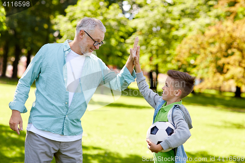 Image of old man and boy with soccer ball making high five