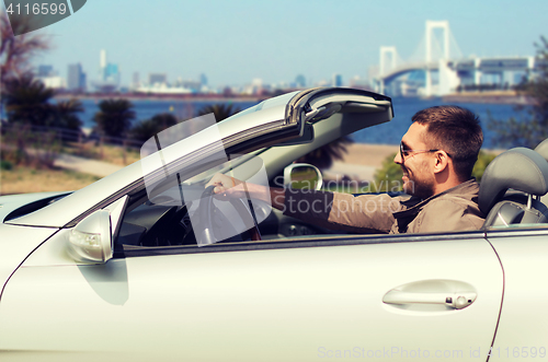 Image of happy man driving cabriolet car in tokyo