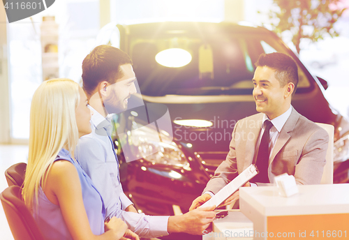 Image of happy couple with car dealer in auto show or salon