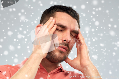 Image of unhappy man suffering from head ache over snow