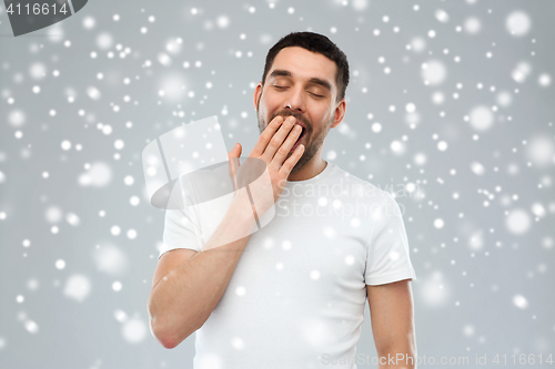 Image of tired yawning man over snow