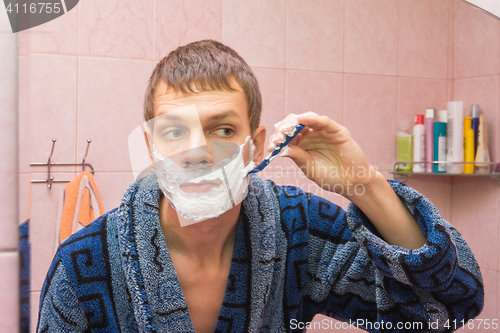 Image of Young man shaves the stubble on his cheek
