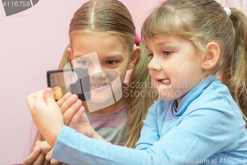 Image of Two children considered a coin through a magnifying glass