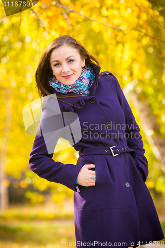 Image of Self-confident girl in a dark blue coat against the background of autumn leaves
