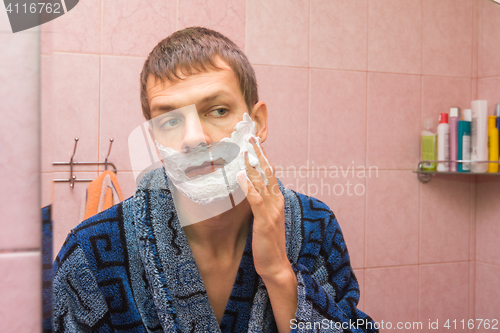 Image of The young man gets shaving foam on face