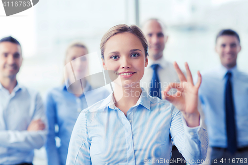 Image of smiling businesswoman showing ok sign in office