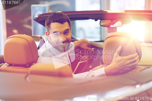 Image of happy man sitting in car at auto show or salon