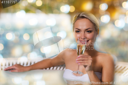 Image of happy woman drinking champagne at swimming pool