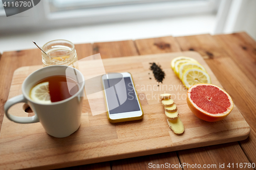 Image of smartphone with cup of lemon tea, honey and ginger