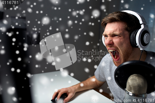 Image of man in headset playing computer video game at home