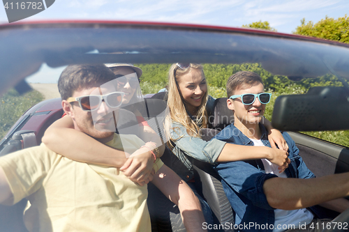 Image of happy friends driving in cabriolet car outdoors