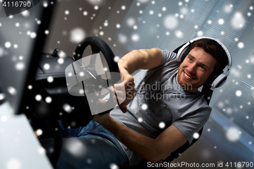 Image of man playing car racing video game at home