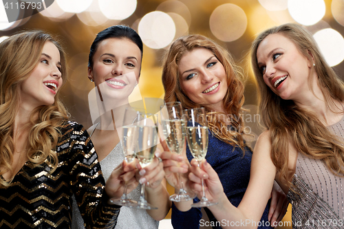 Image of happy women clinking champagne glasses over lights