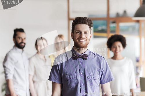 Image of happy young man over creative team in office