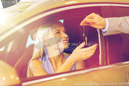 Image of happy woman getting car key in auto show or salon